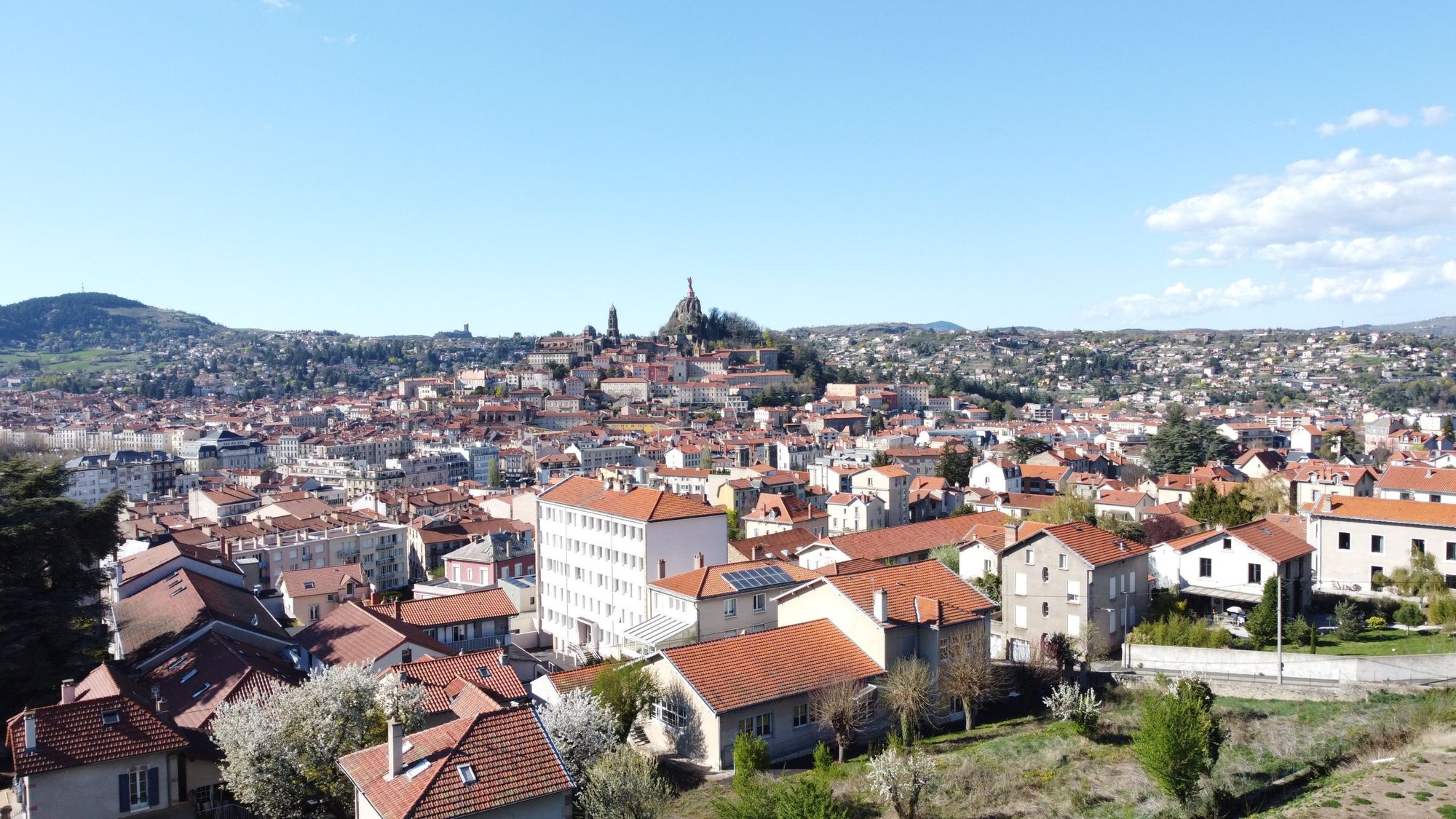 Panorama du Puy-en-Velay : toits de tuiles, cathédrale Notre-Dame et statue Notre-Dame de France sur le rocher Corneille